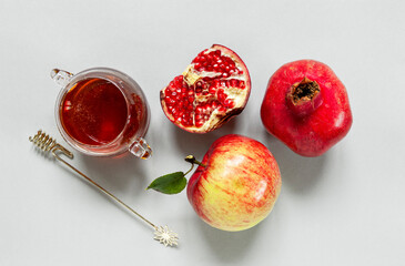  Apples, pomegranate and honey. Concept for Rosh Hashanah the Jewish New Year. Close up on gray...