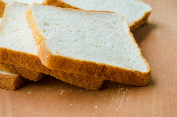 Fresh slices of bread displayed on wooden table. Breakfast concept