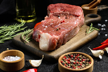 Meat on a cutting board with spices, pepper, rosemary, garlic, salt, vegetable oil