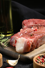 Meat on a cutting board with spices, pepper, rosemary, garlic, salt, vegetable oil