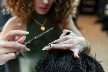 Expert barber meticulously trims and styles a man's hair using scissors, focusing on precision and...