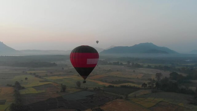 Aerial view of a hot air balloon over serene countryside and mountains at sunrise, Dambulla, Sri Lanka.