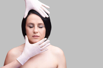 Cosmetic procedure concept with woman's face and hands in gloves on gray background representing...