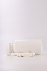 Spilled White Pills from White Plastic Bottle on Minimalist White Background