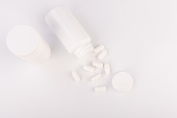 Top-Down View of White Pills and Bottle on White Surface, Pharmaceutical Product Display