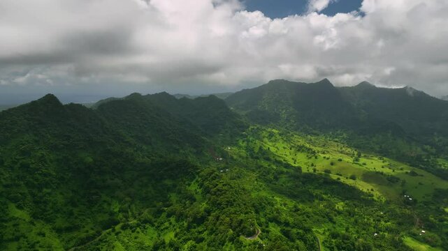 Aerial view of a tropical island landscape with lush greenery, serene clouds, and vibrant mountains, Va`a-o-Fonoti, Samoa.