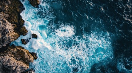 Aerial view of ocean waves crashing against rocky coastline.