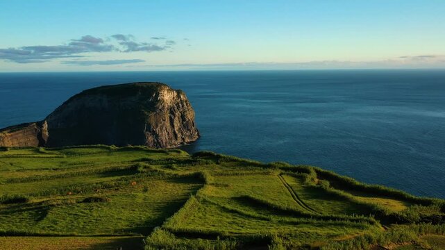 Aerial view of rugged cliffs and lush greenery overlooking the peaceful Atlantic Ocean, Faial, Azores, Portugal.