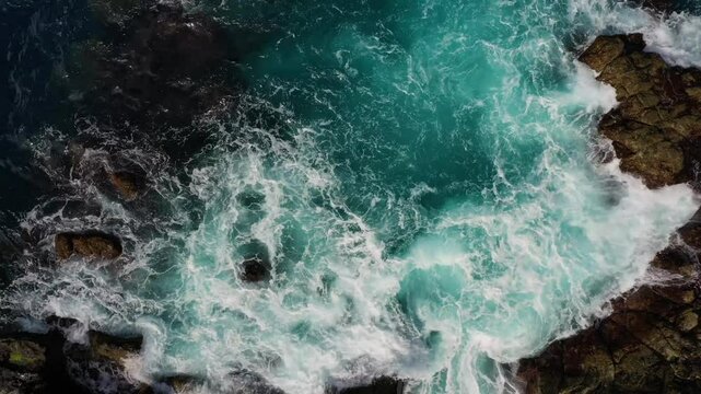 Aerial view of dramatic ocean waves crashing against rugged rocks, Faial, Azores, Portugal.