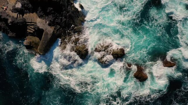 Aerial view of rocky coastline with crashing waves and turbulent ocean, Faial, Azores, Portugal.