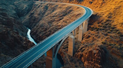 A winding bridge spans a canyon, surrounded by rugged terrain and a flowing river below.