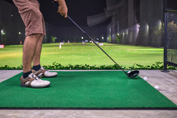 A man practicing with golf swing on golf course at golf driving range