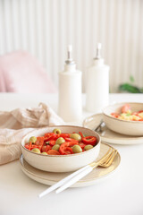 Healthy vegetarian salad with fresh cherry tomato, cucumber, sweet pepper, green olives and lettuce in bowl on white table. Front view