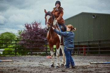 Horse, child and trainer on farm for riding sport, countryside training and equestrian development. Stallion, girl and woman for balance support, practise advice and ranch hobby for exercise outdoor