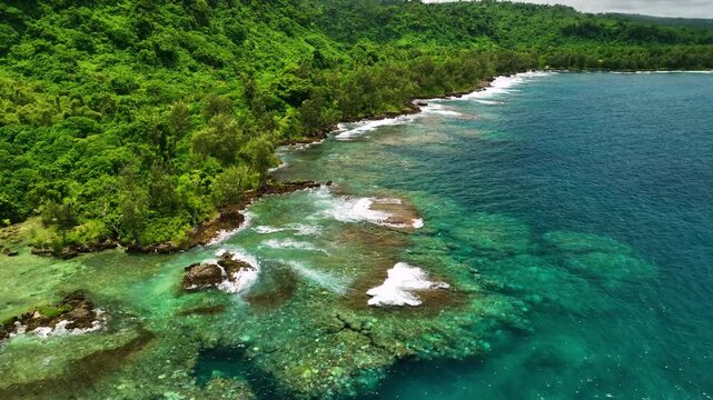 Aerial view of tropical island with lush greenery, vibrant reef, and crashing waves, Shefa Province, Vanuatu.