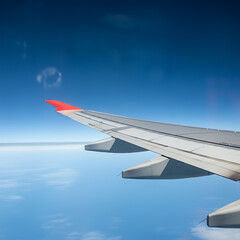 Obraz premium Wing of modern aircraft flying in cloudy blue sky during trip