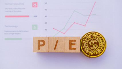 Wooden cube with the word P Slash mark E. It is an abbreviation of Price to Earnings Ratio. Business profitability success growth profitability analytics. Business and financial market concept.