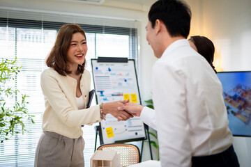 Obraz premium A woman is standing in front of a white board with a smile on her face. She is talking to two other people, one of whom is sitting in a chair. Concept of collaboration and teamwork