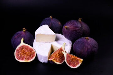 Whole and cut figs with cheese and pepper on a black background. Spicy taste. Mediterranean cuisine.