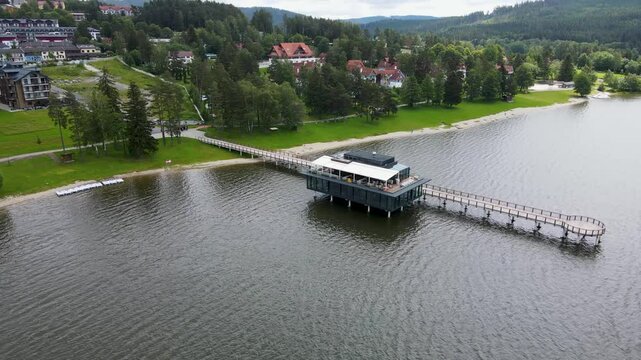 Aerial view of tranquil Lipno Lake with a scenic pier and lush greenery, Lipno nad Vltavou, Czech Republic.