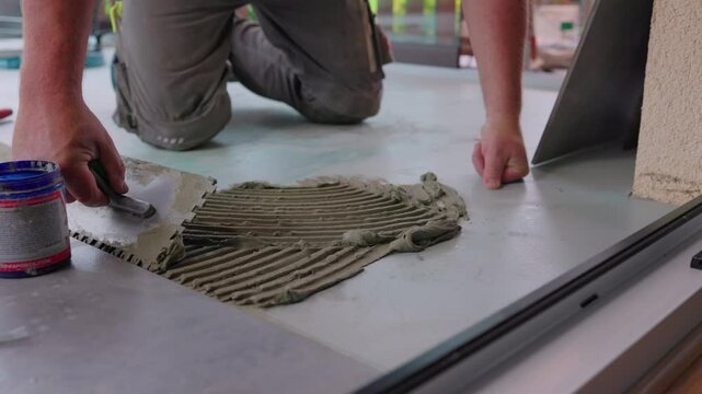 Fliesenleger schneidet Fliese