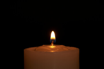 Candles burning against a black background illuminate a hope of faith
