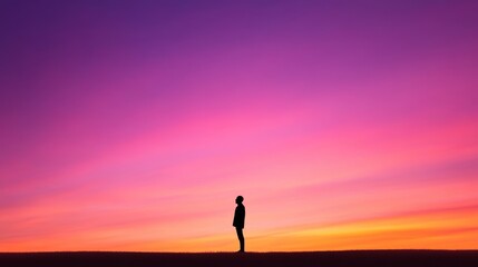 Fototapeta premium A solitary figure silhouetted against a vibrant orange and purple sky, the soft glow of twilight illuminating the horizon.