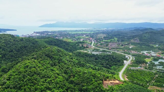 Aerial view of lush green forest and mountains with a serene valley and coastline, Kampung Lubok Buaya, Malaysia.