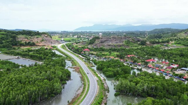 Aerial view of picturesque Kampung Lubok Buaya village surrounded by lush greenery, tranquil river, and scenic mountains, Kuah, Malaysia.