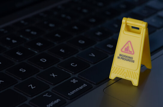 The caution sign, positioned on a keyboard, serves as a visual metaphor for the ongoing development and improvement of digital systems.