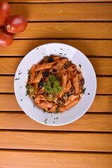 Top view plate of Penne Arrabbiata pasta on dark background. Plate of freshly cooked Penne all'Arrabbiata pasta vertical shot,
