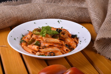 Top view plate of Penne Arrabbiata pasta on dark background. Plate of freshly cooked Penne all'Arrabbiata pasta vertical shot,