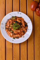 Top view plate of Penne Arrabbiata pasta on dark background. Plate of freshly cooked Penne all'Arrabbiata pasta vertical shot,