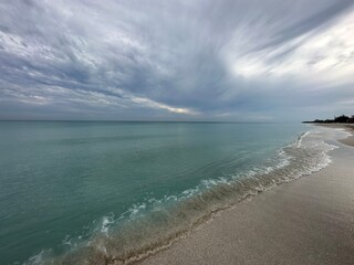 Tranquil beach scene with calm waters and overcast sky, perfect for serene coastal moments and...