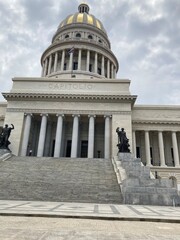 Majestic Capitol building in Havana, Cuba, with a large dome and columns under a partly cloudy sky.