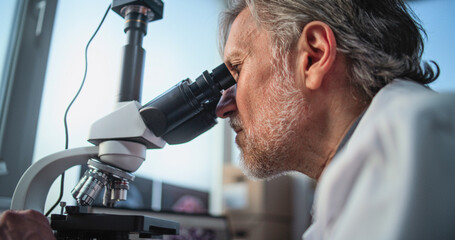 Close up of mature scientist conducting scientific research, analyzing fossil sample under...