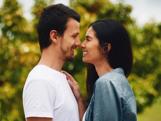 Fototapeta premium Love, peace and smile with couple in park for romance, bonding and summer vacation. Happiness, commitment and care with man and woman relax on date in nature for marriage, support and partnership