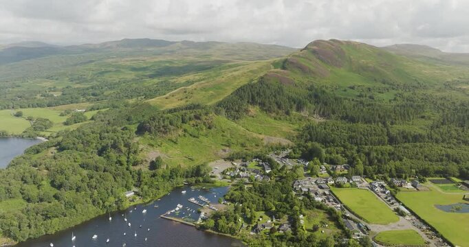 Aerial view of beautiful Loch Lomond surrounded by breathtaking mountains and a picturesque village, Balmaha, United Kingdom.