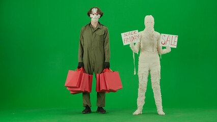 Portrait of person in mummy bandage on chroma key green screen background. Maniac with handful of...
