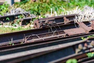 teren rozbiórki stare zardzewiałe i rozebrane tory kolejowe leżące na zielonej trawie w tle krzaki © DP.REPORT