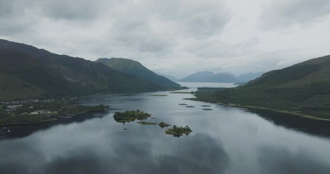 Aerial view of serene Loch Leven surrounded by majestic mountains under a cloudy sky, Glencoe, Scotland.