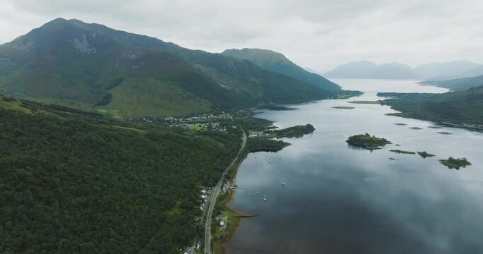 Aerial view of Loch Leven surrounded by beautiful mountains and a winding road, Glencoe, United Kingdom.