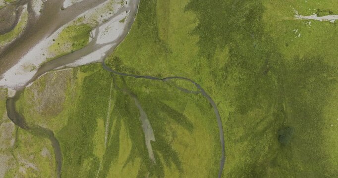 Aerial view of a beautiful river winding through lush green grass in the scenic Scottish Highlands, Kyle, United Kingdom.