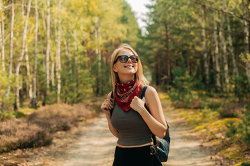 A young white woman tourist with a backpack in a pine forest in summer