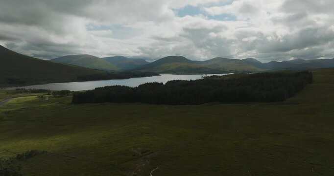 Aerial view of serene Loch Tulla surrounded by majestic mountains and lush forest, Bridge of Orchy, Scotland.