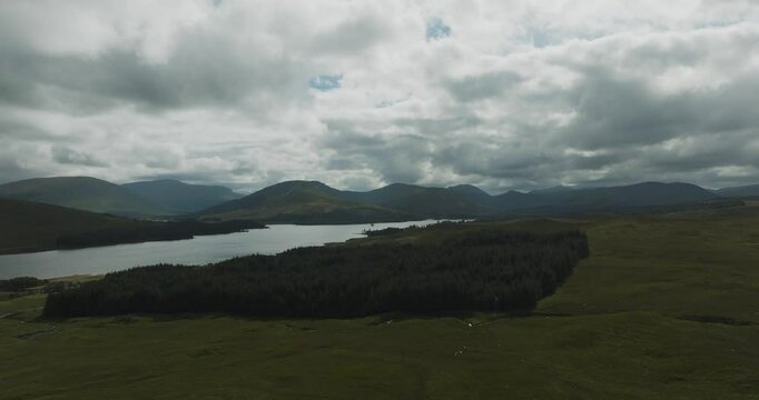Aerial view of serene Loch Tulla surrounded by majestic mountains and lush forest in the Scottish Highlands, United Kingdom.