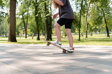 Teenage legs in athletic shoes executing daring skateboard maneuver in lush, green park setting....