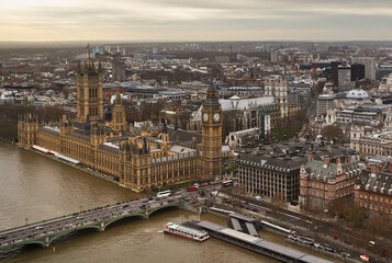 Fototapeta premium Aerial view of the Houses of Parliament and Big Ben alongside the River Thames. Busy bridges and vehicles add life to the historic view of London.