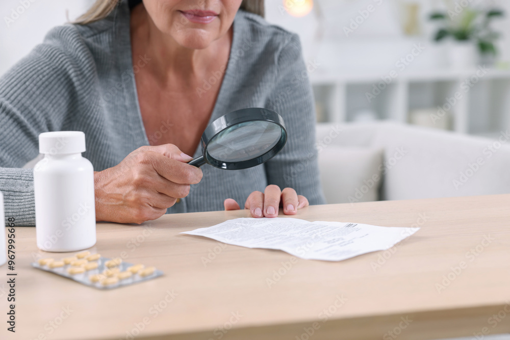 Sticker Senior woman with magnifying glass reading medicine instruction at table indoors, closeup