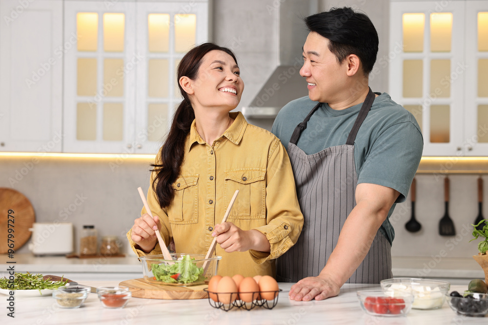 Wall mural happy lovely couple cooking together in kitchen